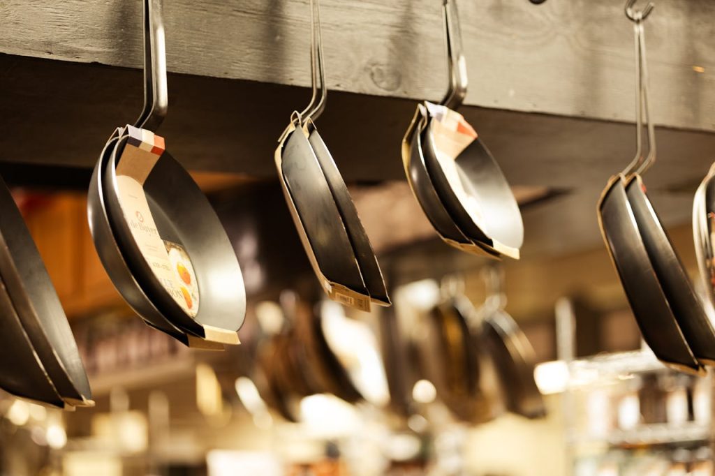 A selection of frying pans hanging in a kitchenware shop for sale.