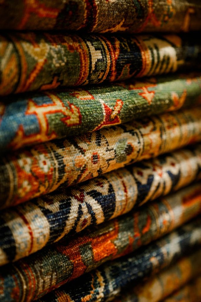 pexels photo 30002534 Close-up view of intricately patterned oriental carpets stacked together.