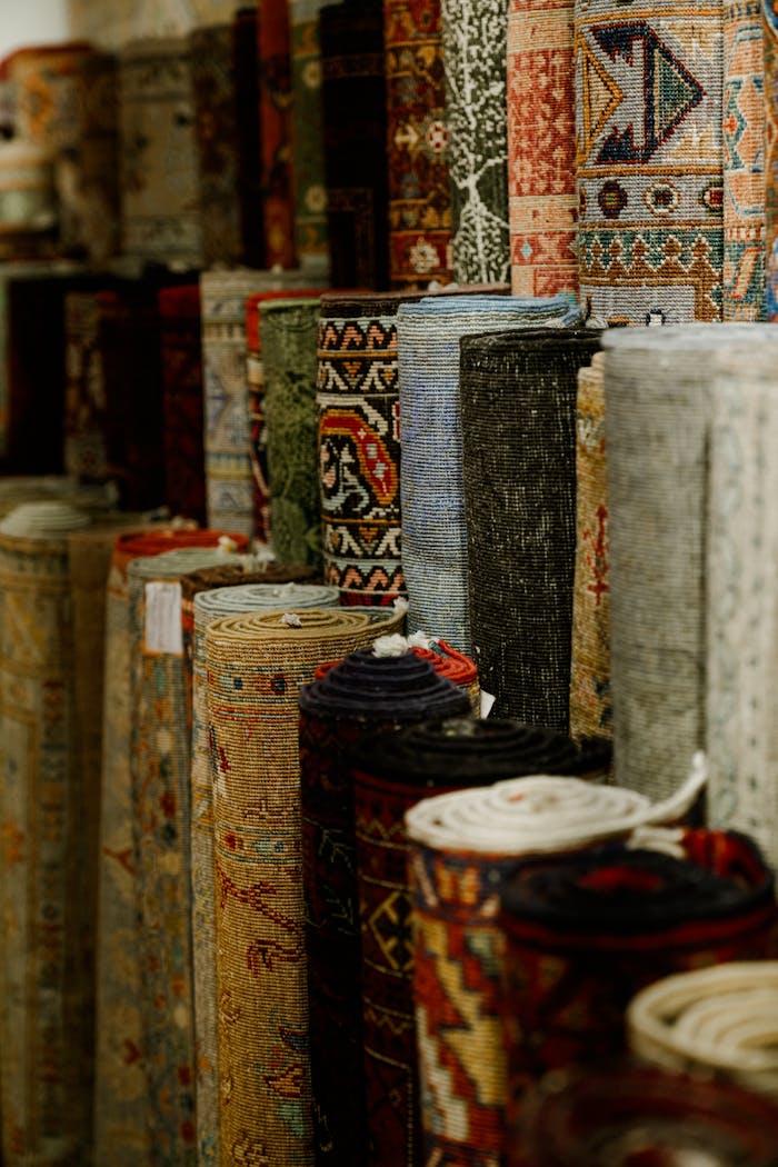A variety of rolled carpets in vibrant colors and patterns on display in a textile shop.