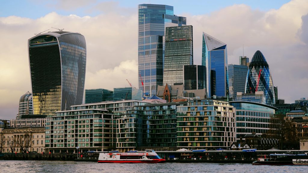 Panoramic view of London's iconic skyscrapers along the Thames River with modern architecture.