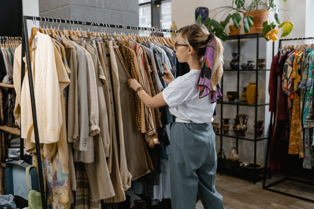 pexels photo 7679720 Woman browsing through clothes on hangers in a stylish boutique setting.